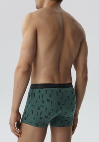 Zielone bokserki z czarnym abstrakcyjnym wzorem, z czarnym pasem w talii z napisem „ATLANTIC”. Teksturowany materiał typu jersey.