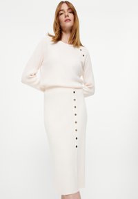 Hellrosa, gerippter Strickpullover mit Schulterknöpfen und einem passenden knielangen Rock mit seitlichem Knopfdetail.