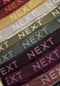 Set de benzi elastice pentru talie în diverse culori, inclusiv burgundy, bej, verde și gri, cu cuvântul "NEXT" brodat proeminent.