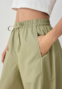Lys grøn, joggers med elastisk talje og snor, der har sidelommer og et glat, tekstureret stof. Ideel til hverdagstøj.