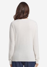 Elfenbensfärgad tröja gjord av mjukt tyg med långa ärmar, rundad halsringning och avslappnad passform, med ribbat avslut och muddar.