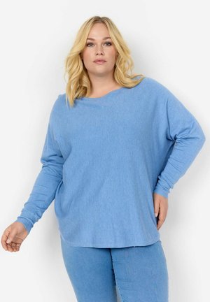 Maglietta a manica lunga di colore azzurro chiaro con scollatura ampia e vestibilità rilassata. Tessuto morbido, orlo arrotondato e maniche con polsini. Abbinata a pantaloni blu coordinati.
