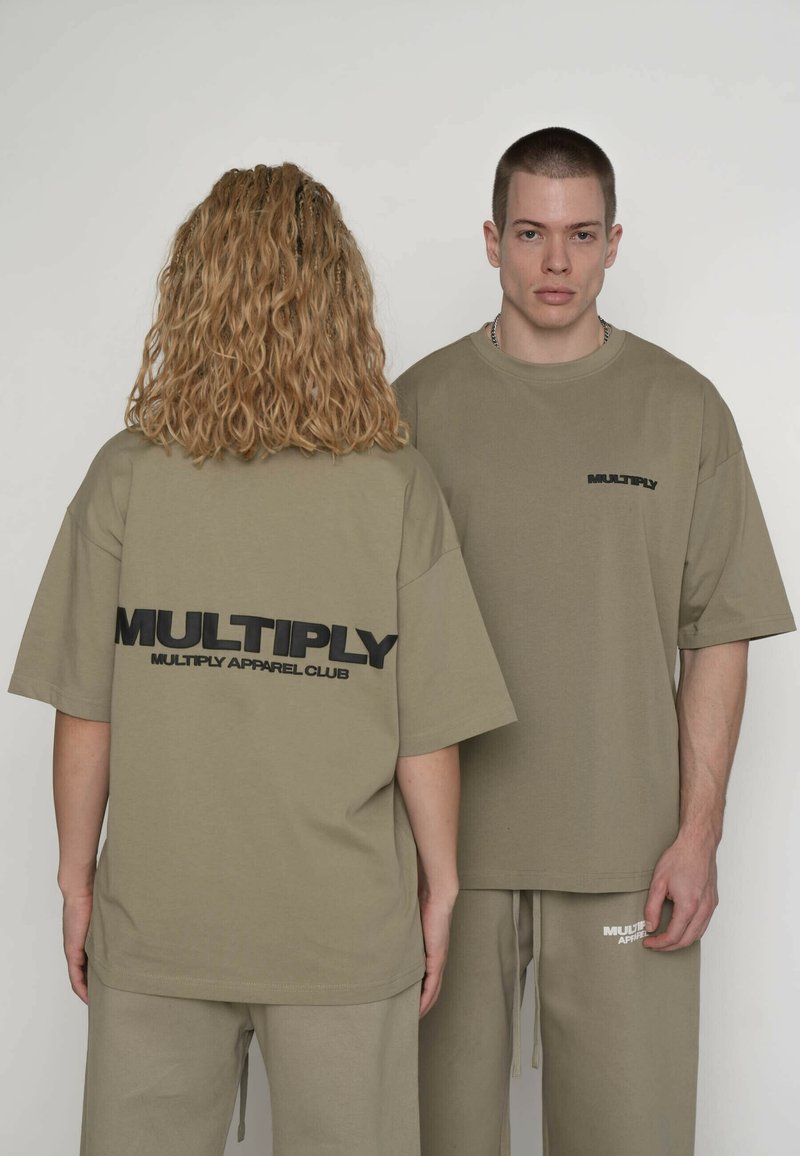 Olivengrønne oversized T-shirts i bomuld med sort tekst "MULTIPLY" på både ryggen og forsiden. Kombineret med matchende bukser. Simpelt design.