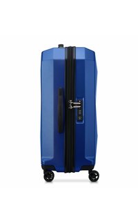 Valigia rigida blu con superficie texture, cerniera nera, lucchetto combinato, maniglia laterale e quattro ruote multidirezionali.