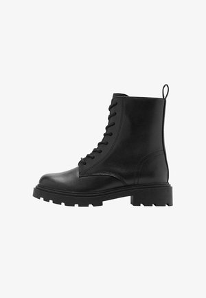 Bottines en cuir noir avec un bout rond, un laçage à l'avant et une semelle robuste. Comprend une languette à l'arrière pour un enfilage facile.