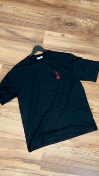 Svart bomulls t-skjorte med korte ermer, rund hals, og en rød brodert logo med et "K" og en kløver på venstre bryst.