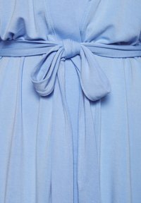 Svetlomodré sukňové šaty s opaskom v páse, jemnou textúrou a splývavými záhybmi. Textília má hladký povrch a úhľadné stehy.