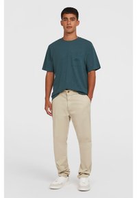 Teal kortærmet skjorte med en brystlomme, parret med beige chinos og hvide sneakers. Glat stof og afslappet pasform.
