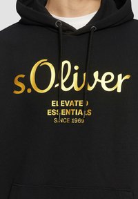 Zwarte hoodie met gouden tekst "s. Oliver" en "ELEVATED ESSENTIALS SINCE 1969." Voorzien van trekkoorden en een voorzak. Gemaakt van katoen.