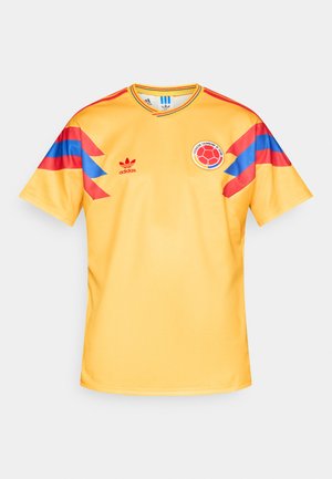 Κίτρινη ποδοσφαιρική φανέλα με μπλε και κόκκινες λεπτομέρειες στα μανίκια. Διαθέτει στρογγυλή λαιμόκοψη, λογότυπο Adidas και κυκλικό λογότυπο ομάδας στο στήθος.