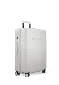 Valise rigide en blanc mat avec des rainures horizontales, poignée télescopique, serrure à combinaison et quatre roues noires pour la mobilité.