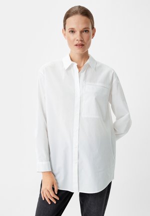 Camicia bianca con colletto, maniche lunghe e tasca sul petto. Realizzata in tessuto liscio con una vestibilità comoda e orlo curvo.