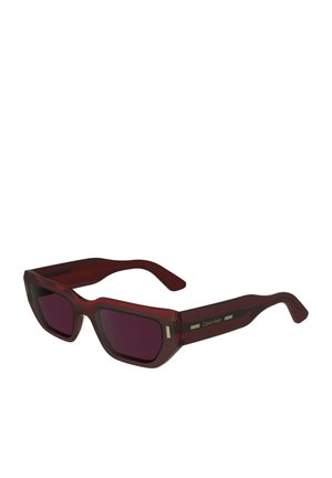 Occhiali da sole Calvin Klein con forma rettangolare, montatura traslucida rossa scura, lenti scure e dettagli dorati sulle astine.