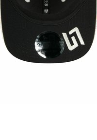 Schwarze Baseballmütze mit flachem Schirm, ausgestattet mit einem glänzenden Logo-Aufkleber und weißen gestickten Akzenten. Strukturierter Stoff mit Nähdetails.