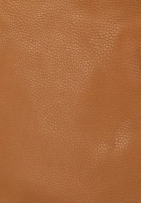 Close-up van een gestructureerd lichtbruin lederen oppervlak met kleine natuurlijke nerfpatronen en een subtiele glans.