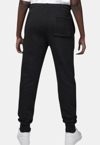 Pantaloni della tuta neri con vita elasticizzata, gambe affusolate e tasca posteriore. Realizzati in un materiale morbido, progettati per comfort e facilità di movimento.