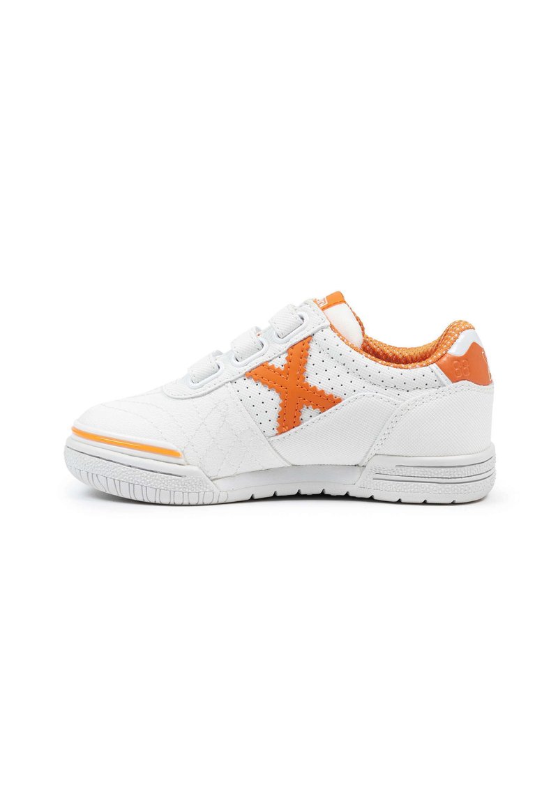 Zapatilla blanca con acentos naranjas, que presenta una "X" naranja en el lado, cuello acolchado y correas de Velcro sobre una suela plana blanca.
