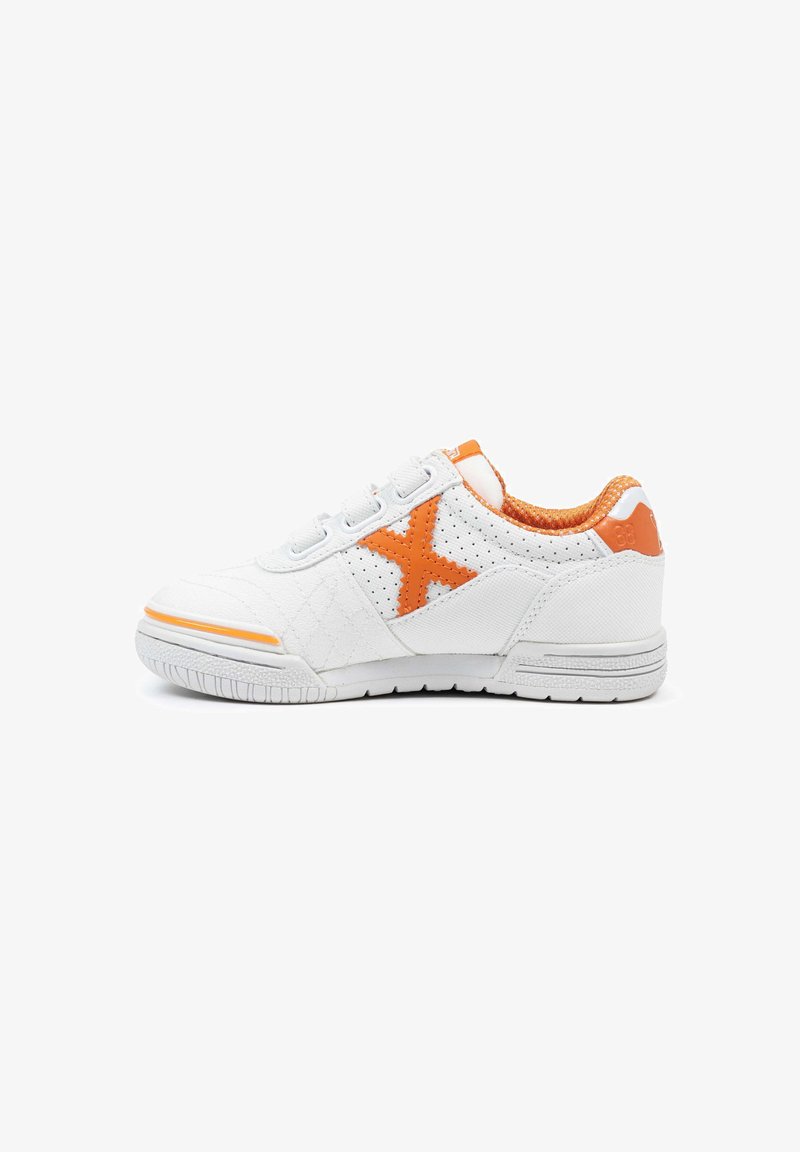 Zapatilla blanca con acentos naranjas, que presenta una "X" naranja en el lado, cuello acolchado y correas de Velcro sobre una suela plana blanca.