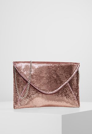 Pochette enveloppe en sequins or rose brillant avec une bandoulière chaîne argentée sur une surface blanche sur fond gris.