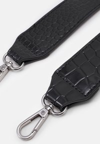 Černý pásek z umělé kůže s krokodýlím motivem; obsahuje kovové komponenty ve stříbrné barvě a karabiny na obou koncích pro připevnění.