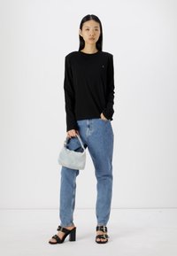 Μαύρη μπλούζα με μακριά μανίκια, ανοιχτό μπλε τζιν παντελόνι, μαύρες σανδάλι με block τακούνι και ανοιχτό μπλε τσάντα. Απλός, χωρίς διακοσμήσεις σχεδιασμός.