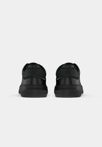 Zwarte sneakers met een glad bovenwerk van synthetisch materiaal, een ronde neus, een dikke rubberen zool en geperst merk op de hiel en zijkant.