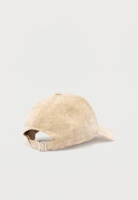 Gorra de béisbol beige con tela texturizada, visera curva y correa metálica ajustable en la parte trasera. Cuenta con una corona redondeada.