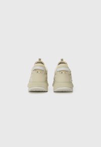 Pair of beige athletic shoes featuring a smooth upper, rounded shape, pull tab on the heel, and textured rubber outsole.