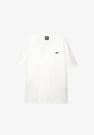 T-shirt bianca a maniche corte con piccolo logo nero sul petto sinistro e collo rotondo, mostrata su uno sfondo bianco semplice.