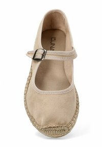 Zapato estilo Mary Jane en color beige con un exterior de suave ante, suela plana de yute y una correa ajustable con hebilla de metal.