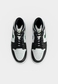 Ζευγάρι sneakers ψηλού τύπου με λευκά, μαύρα και πράσινα πάνελ, μαύρα κορδόνια και διάτρητες μύτες, σε θέα από πάνω σε λευκό φόντο.