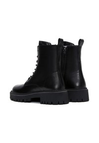 Bottines en cuir noir avec lacets et fermeture éclair, dotées d'une semelle en caoutchouc épaisse et d'une texture lisse. Tailles à l'arrière pour un enfilage facile.