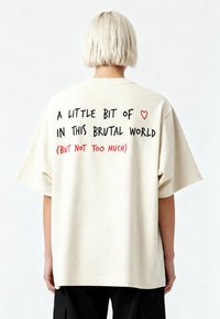 Beidzot kokvilnas T-krekls, kas raksturīgs ar pārāk lielu piegriezumu, īsām piedurknēm un tekstu aizmugurē: "Mazliet ❤️ šajā brutālajā pasaulē (BET NE PAR DAUDZ)."