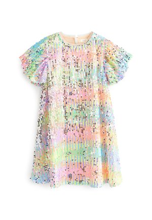 Enfant portant une robe pastel à sequins et des bottes de pluie arc-en-ciel scintillantes, debout sur l'herbe près de bannières colorées en tissu et d'une tente décorée.