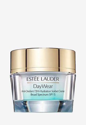 Krem Estee Lauder DayWear w przezroczystym słoiku z złotą pokrywką. Etykieta zawiera zielony i czarny tekst. Zawiera filtr SPF 15 oraz właściwości antyoksydacyjne.