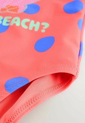 Țesătură de costume de baie în nuanțe de corali, cu buline mari albastre, care prezintă un text ce spune "BEACH?" lângă o cusătură decorativă, guler plat și textură netedă.