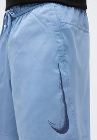 Αθλητικό σορτς ανοιχτού μπλε με ελαστική μέση και σκούρο μπλε, υφή με το λογότυπο Nike swoosh στο αριστερό πόδι.