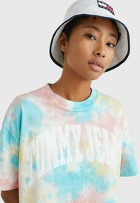 T-shirt a maniche corte in tie-dye di colori pastello con scollo rotondo e grande testo "TOMMY JEANS" in bianco sulla parte anteriore.
