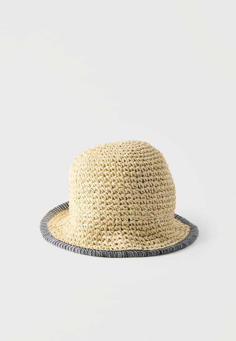 Chapeau bob en paille tissée beige avec une calotte arrondie et un bord roulé rayé noir et blanc.