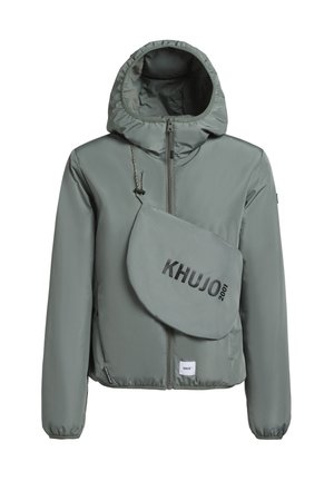 Šviesiai pilkas pūkinis švarkas su gaubtu, priekinis užtrauktukas ir elastiniai rankogaliai. Turi nuimamą pilką petnešą su užrašu "KHUJO 2001".