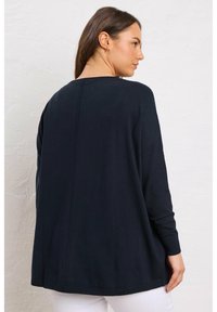 Maglione oversize blu navy con maniche lunghe, scollo rotondo e polsi a coste, con un dettaglio di cucitura centrale sul retro.