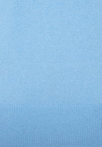 Tissu tricoté bleu clair avec une texture lisse et un ourlet côtelé. La surface est homogène, affichant un motif fin dans tout le tissu.
