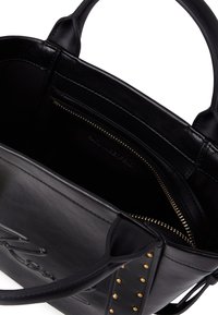 Svart skinnveske med doble håndtak, gullnagler på sidebåndene, og en innvendig glidelåslomme.