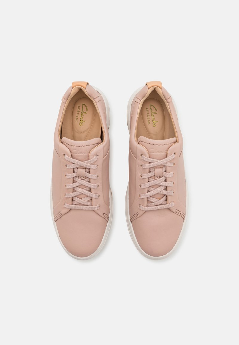 Zapatillas de cuero rosa claro con puntera redondeada, cordones planos y suela de goma blanca. Presentan una textura suave y un diseño minimalista.