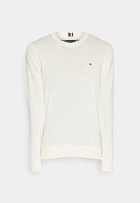 Witte gebreide trui met lange mouwen, ronde hals en een klein rood en blauw logo op de borst. Heeft ribgebreide manchetten en onderkant.