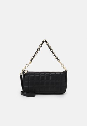 Černá obdélníková prošívaná kabelka se zlatými a černými řetízkovými popruhy a dalším dlouhým černým koženým popruhem na bílém pozadí.