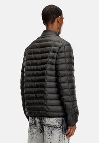 Black puffer jacket with a quilted design, featuring a mock collar and side zip pockets. Smooth texture and lightweight material.