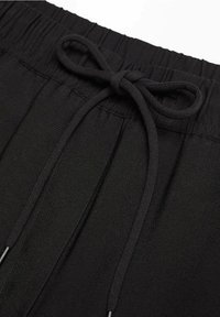 Sorte shorts med snoretræk lavet af blødt stof har en elastisk talje og en bundet sløjfe foran. Glat tekstur med minimal detaljering.