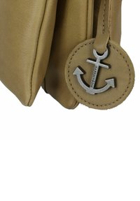 Borsa in pelle color tan con un charm a forma di ancora metallica arrotondata attaccato. La borsa presenta una superficie liscia e un design morbido e alla moda.