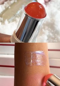 Gjennomsiktig ferskenpinne med en blank kuppelformet tupp, påført huden og avslører en skimrende rosa base med en lett reflekterende finish.